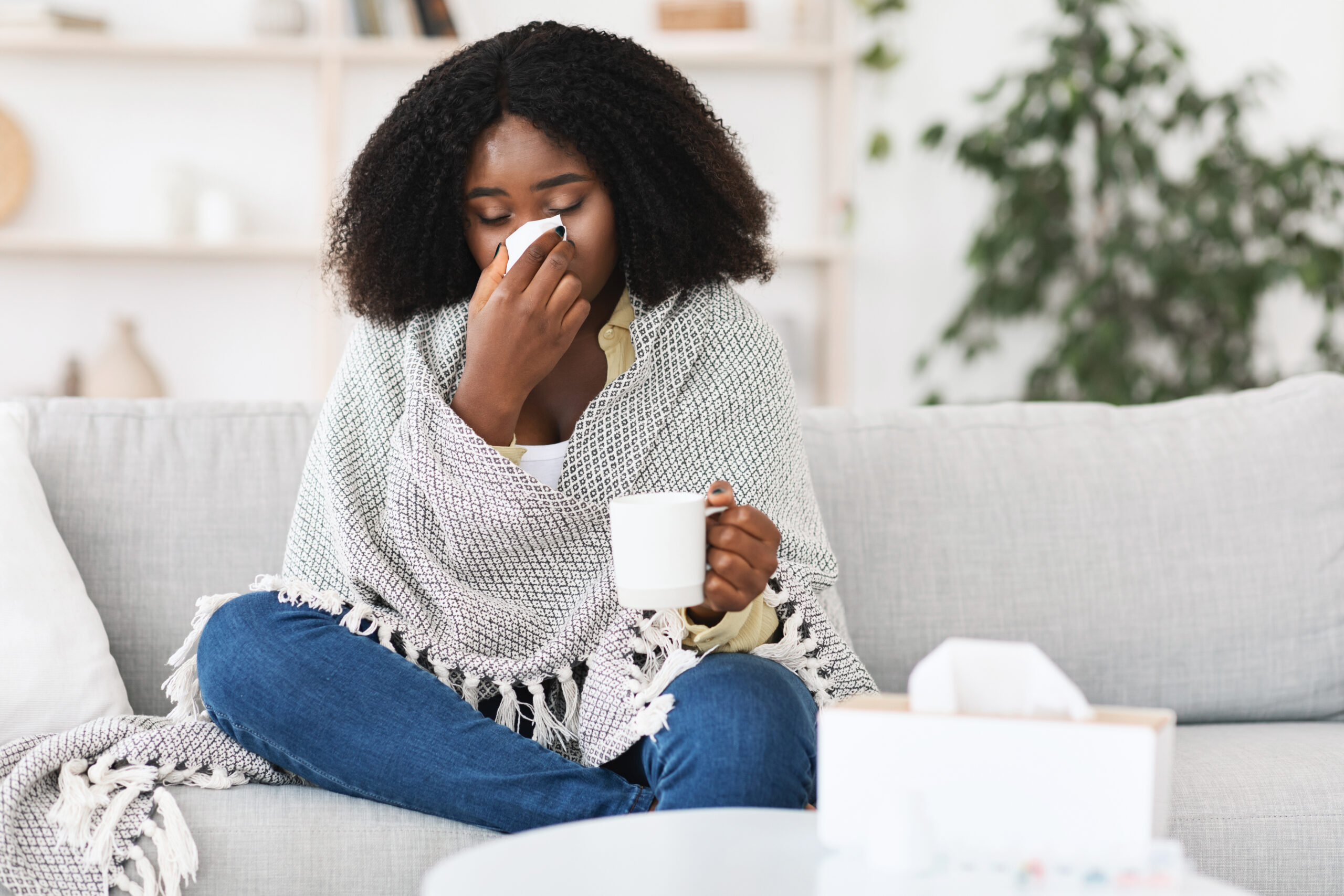 A woman is stuck inside with a runny nose and sore throat, common symptoms of the cold and flu.